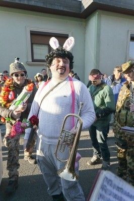 Ein Mann in einem weißen Kostüm mit Hasenohren und einer Trompete steht in einer Menschenmenge, möglicherweise bei einem Festival.