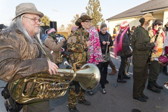Eine Gruppe von Menschen in Camouflage-Uniformen und Hüten spielt draußen Musikinstrumente.