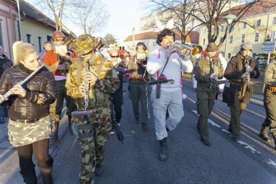 Eine Gruppe von Menschen in Militäruniformen, die Musikinstrumente spielen, marschiert die Straße entlang.