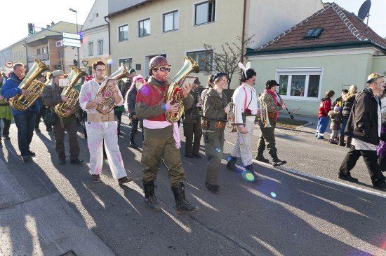 Eine Gruppe von Menschen in Kostümen marschiert bei einem Umzug und spielt Blechblasinstrumente.