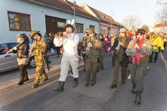 Eine Gruppe von Menschen in Militäruniformen und Hasenohren, die mit Musikinstrumenten auf einer Straße marschieren.