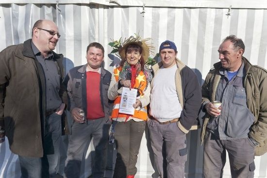 Fünf Personen stehen nebeneinander, lächeln und posieren für ein Foto. Die Frau in der Mitte hält ein Zertifikat.
