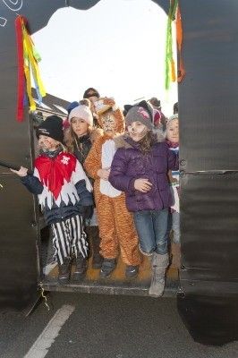 Eine Gruppe von Kindern in verschiedenen Kostümen steht in einem dekorierten Anhänger, möglicherweise für eine Parade oder Veranstaltung.