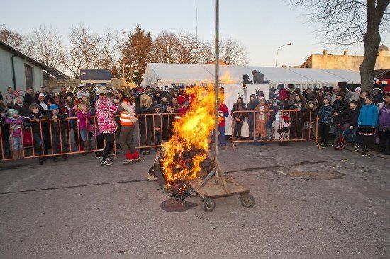 Eine Menschenmenge beobachtet ein brennendes Feuer auf einem rollenden Karren in einem Außenbereich, möglicherweise während eines Festivals.
