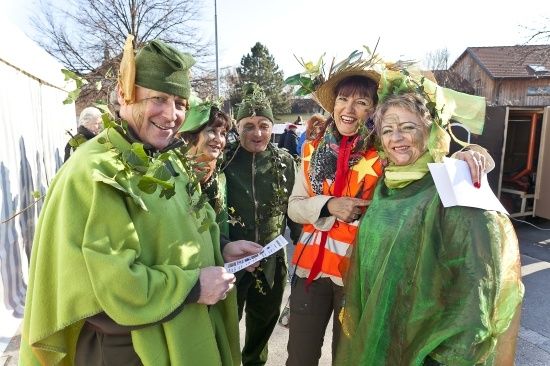 Eine Gruppe von Menschen in grünen Kostümen und Hüten posiert für ein Foto auf einer Straße.
