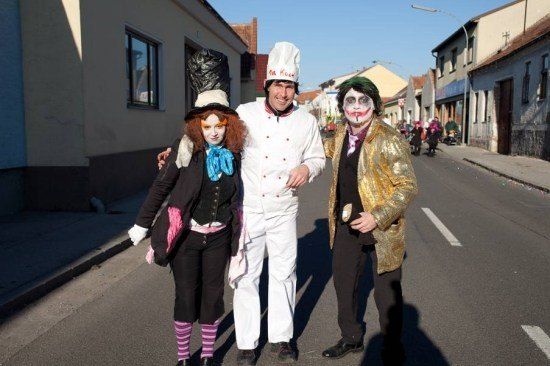 Drei Menschen in Kostümen posieren für ein Foto auf einer Straße. Eine Frau in einer Hexenkostüm, ein Mann in einer Kochmütze und ein Mann in einem Joker-Kostüm.