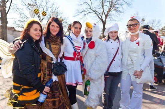 Eine Gruppe von Frauen in verschiedenen Kostümen, darunter ein Huhn, eine Biene und eine Krankenschwester, stehen zusammen im Freien.