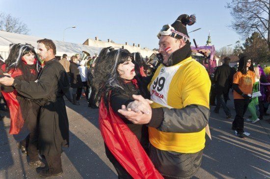 Ein Paar in Halloween-Kostümen tanzt auf einer Straße, umgeben von anderen Menschen in Kostümen.