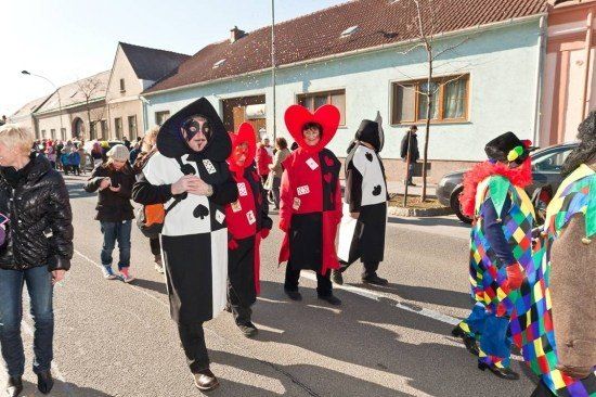 Eine Gruppe von Menschen in Kostümen geht während eines Umzugs die Straße entlang. Einige tragen Masken und Hüte.