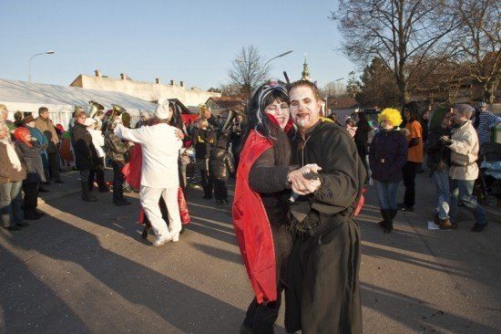 Eine Gruppe von Menschen in Kostümen tanzt während eines Festivals auf der Straße.