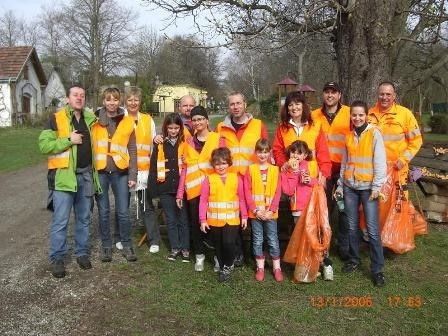 Eine Gruppe von Menschen in Warnwesten, einschließlich Erwachsener und Kinder, steht auf einer Rasenfläche, möglicherweise für eine Gemeinschaftsaktion zur Müllentsorgung.