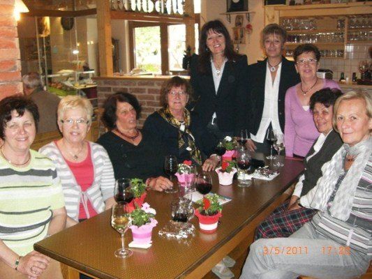 Eine Gruppe von Frauen sitzt in einem Restaurant um einen Tisch herum, lächelt und posiert für ein Foto. Sie halten Weingläser und es gibt Blumen auf dem Tisch. Das Bild hat einen Zeitstempel vom 3.5.2011 17:28.