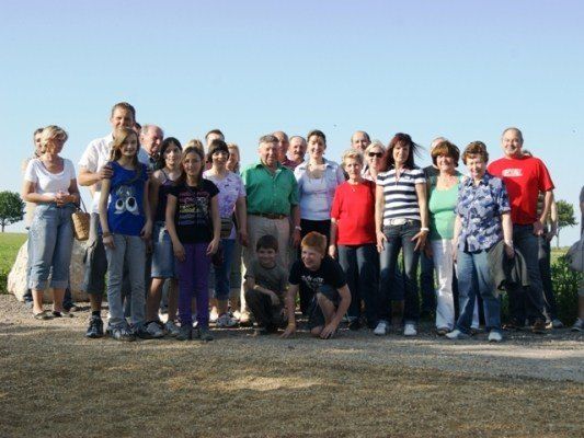 Eine Gruppe von Menschen, einschließlich Erwachsener und Kindern, steht zusammen auf einem Feld und posiert für ein Foto.