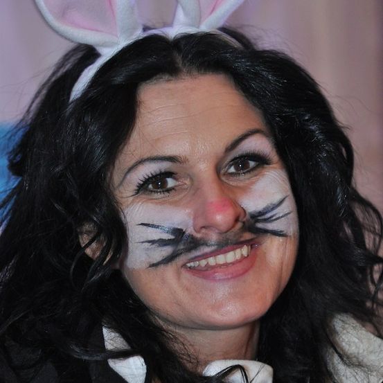 Eine Frau in einem Hasenkostüm mit Gesichtsbemalung, lächelt für ein Foto.