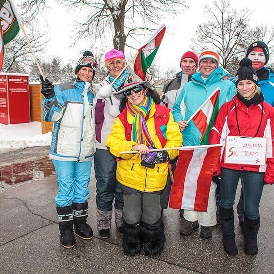 Eine Gruppe von Menschen in Winterkleidung und mit Flaggen posiert für ein Foto in einem verschneiten Bereich. Die Flaggen stammen aus Ungarn und Österreich.
