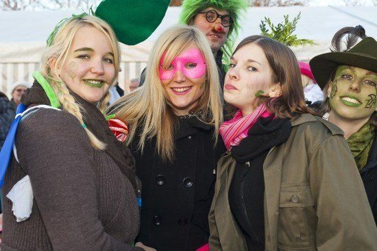 Vier Frauen und ein Mann, alle mit grüner Gesichtsbemalung, posieren für ein Foto. Die Frau links hat grüne Blätter in den Haaren. Die Frau in der Mitte trägt eine pinke Maske. Die Frau rechts hat einen grünen Hut.