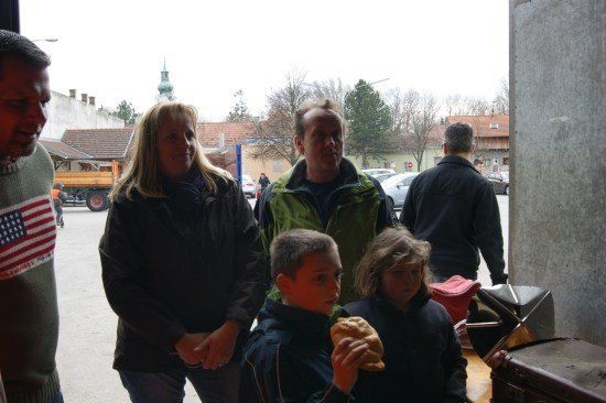 Eine Familie mit fünf Personen steht draußen, ein Junge isst ein Sandwich und ein Mann trägt einen amerikanischen Flaggenschal.