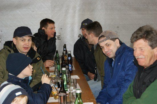 Eine Gruppe von Männern und einem Kind, die um einen Tisch mit verschiedenen Flaschen und Gläsern sitzen.