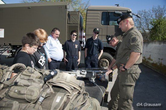 Militärpersonal und Zivilisten inspizieren militärische Ausrüstung und Ausrüstung an einem sonnigen Tag.
