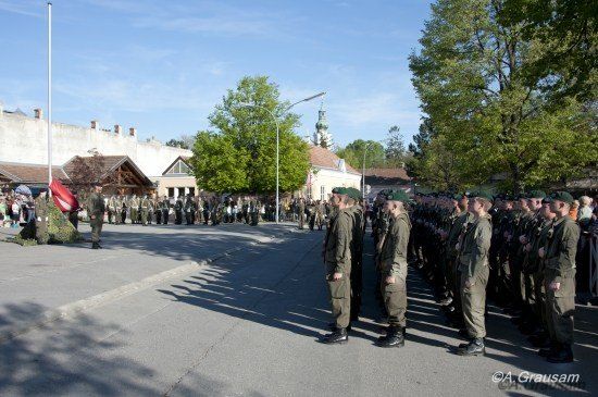 Eine Gruppe Soldaten in Uniform steht an einem sonnigen Tag in Formation vor einem Gebäude.