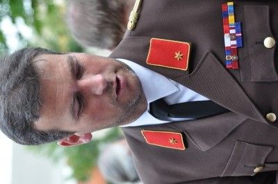 Ein Mann in Uniform mit Medaillen auf der Brust schaut nach unten, möglicherweise bei einer offiziellen Veranstaltung.