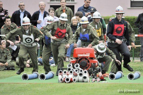 Eine Gruppe von Menschen in Militäruniformen nimmt an einem Rennen auf einem Rasenfeld teil, während Zuschauer von hinten zusehen.