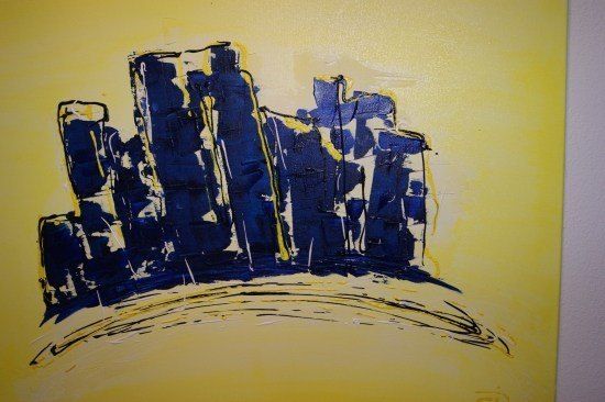 Eine abstrakte Malerei mit gelbem Hintergrund und blauen geometrischen Formen, die Gebäude oder Strukturen ähneln.