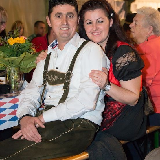 Ein Mann und eine Frau in traditioneller deutscher Kleidung lächeln und posieren für ein Foto bei einer festlichen Veranstaltung.