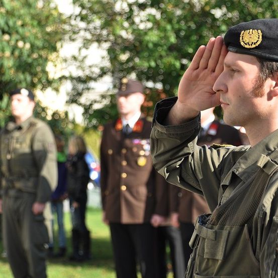 Ein Soldat in Uniform salutiert vor einer Gruppe anderer Soldaten.