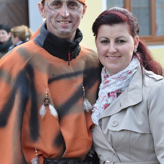 Ein Mann in einem Tiger-Kostüm und eine Frau in einem beigefarbenen Trenchcoat lächeln für ein Foto.