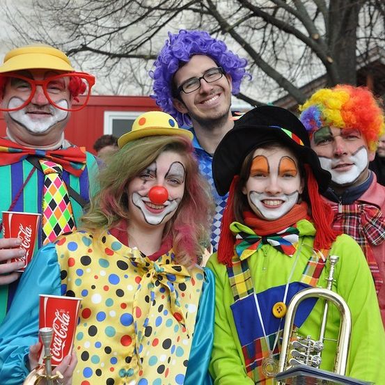 Eine Gruppe von Menschen, die als Clowns verkleidet sind, halten Tassen und Musikinstrumente und posieren für ein Foto.