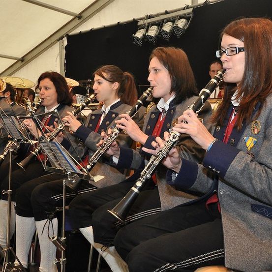 Eine Gruppe junger Frauen in Uniform spielt Klarinetten in einer Band während einer Aufführung.