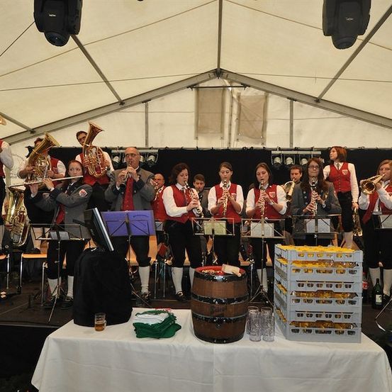 Eine Gruppe von Musikern in traditioneller Kleidung spielt auf der Bühne mit verschiedenen Instrumenten unter einem Zelt.
