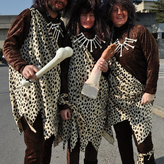 Drei Personen in Leoparden-Kostümen mit Knochen-Accessoires, die zusammen auf einer Straße stehen.