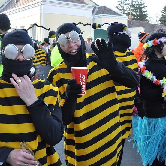Eine Gruppe von Menschen, die als Bienen verkleidet sind, einer hält einen Coca-Cola-Becher, steht in einer Parade.