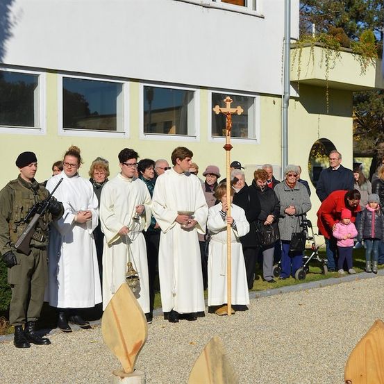 Eine Gruppe von Menschen in weißen Gewändern und mit einem Kreuz haltend stehen vor einem Gebäude mit einem Kreuz oben.