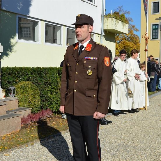 Ein Militäroffizier steht vor einem Denkmal mit einer Gruppe von Menschen in weißen Roben hinter ihm.