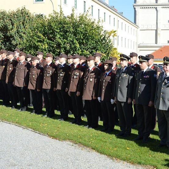 Eine Gruppe von Militärangehörigen in Uniform steht in einer Reihe auf einem Rasen vor einem Gebäude.