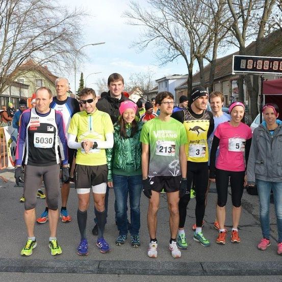 Eine Gruppe von Läufern in verschiedenen farbigen Shirts und Turnschuhen steht in einer Reihe auf einer Straße.