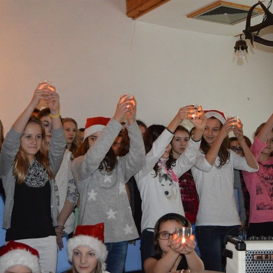 Eine Gruppe junger Mädchen mit Weihnachtsmützen, die Kerzen in den Händen halten, wahrscheinlich für eine Weihnachtsfeier.
