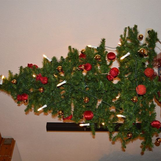 Ein Weihnachtsbaum mit roten und goldenen Kugeln hängt von der Decke, geschmückt mit weißen Lichtern.