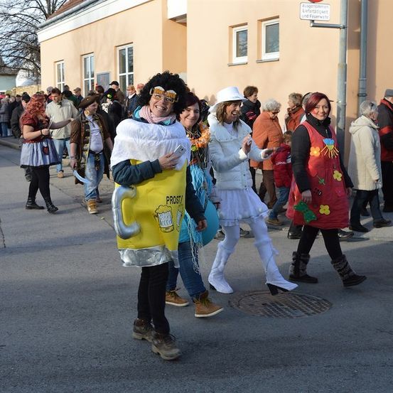 Eine Gruppe von Menschen in Kostümen geht eine Straße entlang, einer ist als Bierkrug verkleidet.