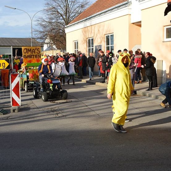 Eine Gruppe von Menschen in Kostümen, darunter ein Pikachu-Kostüm, gehen während eines Umzugs auf einer Straße.
