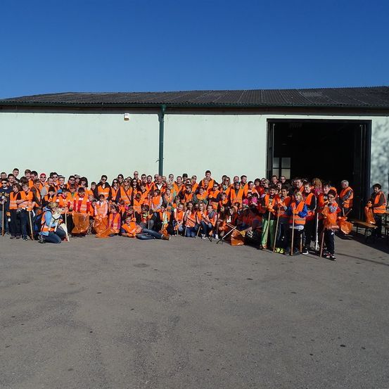 Eine große Gruppe von Menschen in orangefarbenen Westen posiert für ein Foto vor einem Gebäude.