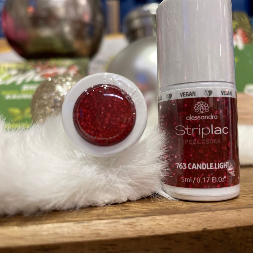 Ein Nahaufnahme eines roten glitzernden Kosmetikprodukts, Alessandro Striplac Peel & Soak, auf einem weißen Pelztuch mit einem verschwommenen Hintergrund.