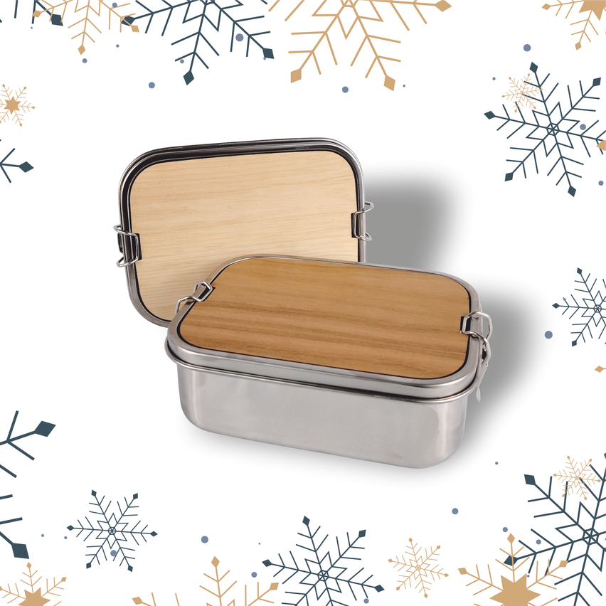 Eine Edelstahl-Lunchbox mit Holzdeckel und Scharnieren ist auf einem weißen Hintergrund mit Schneeflocken geöffnet.