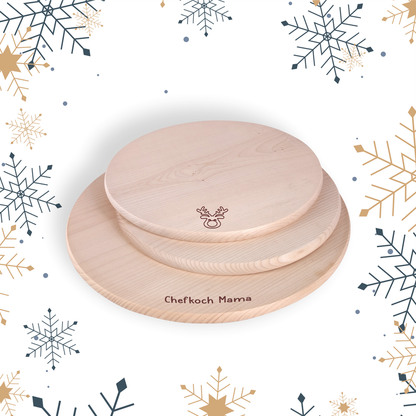 Drei hölzerne Teller mit einem Rentierlogo und den Worten 'Chefkoch Mama' auf der Unterseite, umgeben von Schneeflocken.