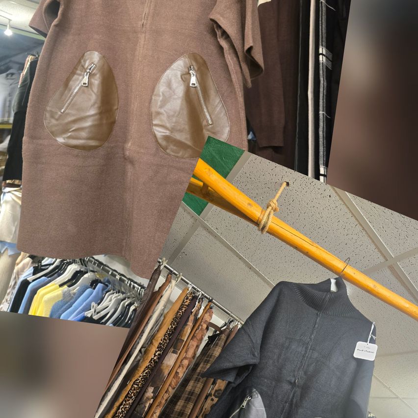 Ein braunes Kleid mit braunen Lederpatches und Reißverschlüssen hängt an einer Stange. Darunter ist ein Kleiderständer mit verschiedenen farbigen Kleidungsstücken ausgestellt. Im Vordergrund hängt ein gelber Stab mit einem schwarzen Pullover.