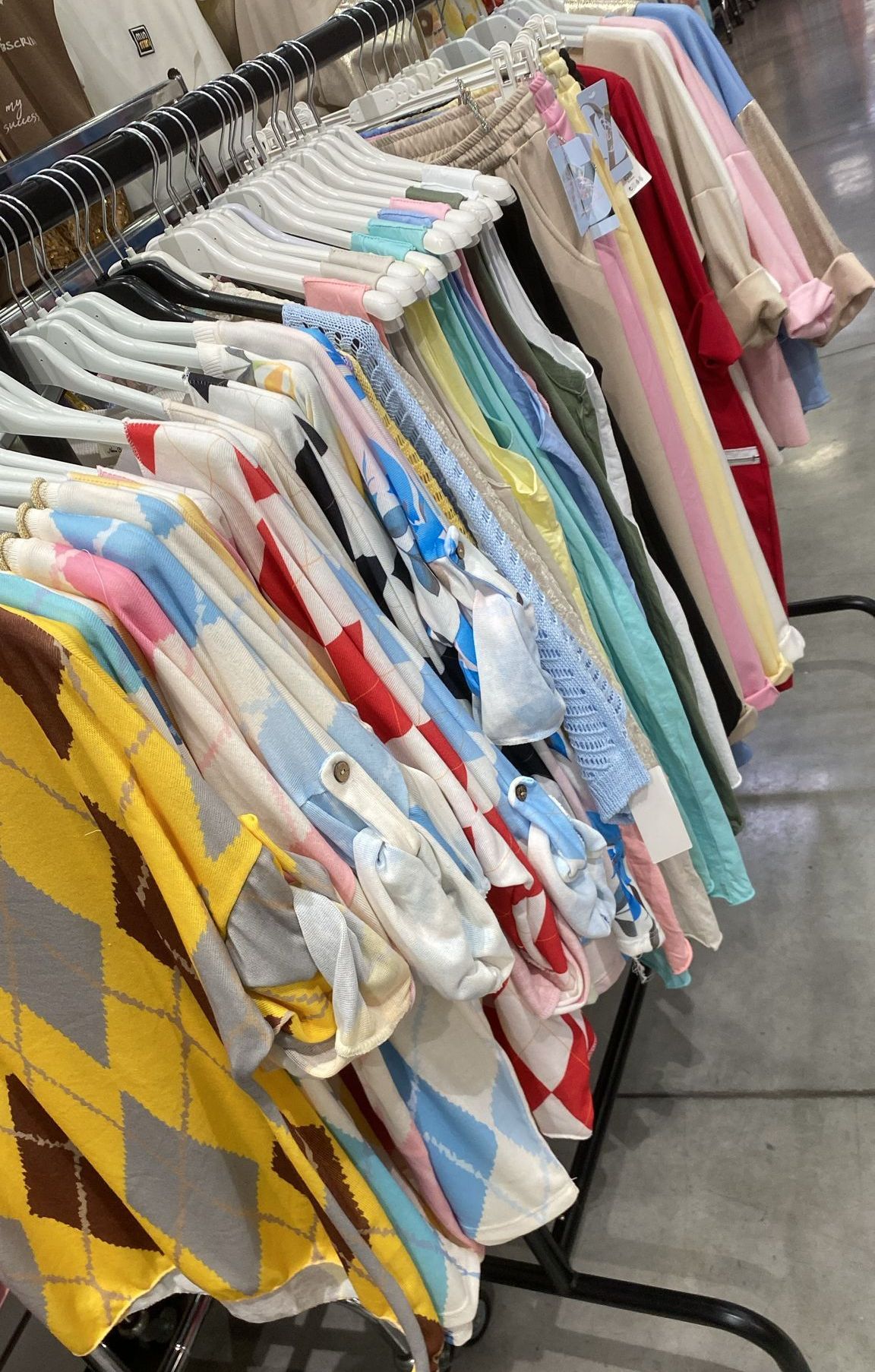 A rack filled with a variety of colorful clothes, including shirts with different designs and patterns. The rack is set up in a store or clothing display area.