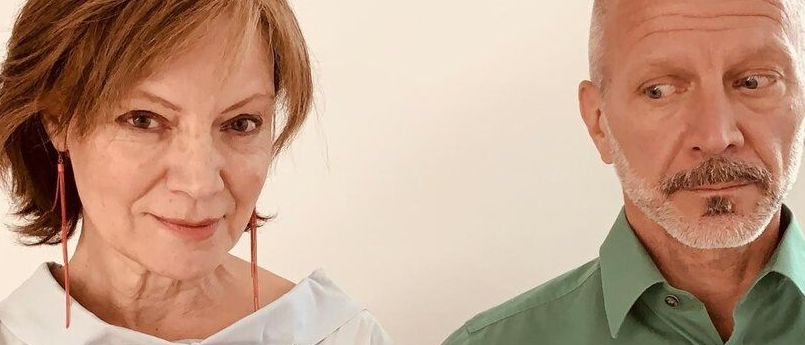 Eine ältere Frau mit einem herzförmigen Kissen auf der Brust und einem Mann in einem grünen Hemd posieren für ein Foto.